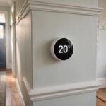 A contender for best smart thermostat UK 2026: modern smart thermostat displaying 20 degrees on a UK hallway wall